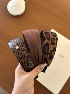 Detailaufnahme der Texturen von Leopardenmuster und braunen Vintage Stirnbändern für Damen