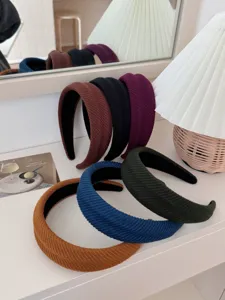Assorted wide knitted headbands with vertical stripe textures displayed on a white table