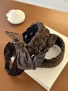 Detail shot of leopard print velvet headbands with bow and braided textures on a book.