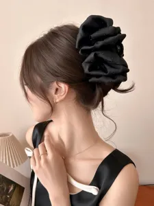 Detailed view of an oversized black bubble hair claw clip used for a bun hairstyle
