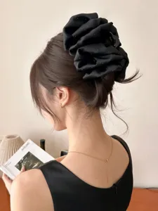 Detailed side view of a large black starry bow hair claw clip on an elegant bun hairstyle.
