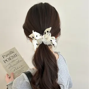 Sweet polka dot bow scrunchie for women, elegant ponytail hair tie styling.