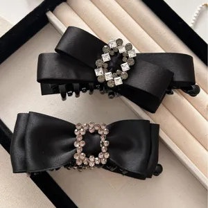 Elegant black satin bow hair claw clips with sparkling rhinestone buckles in a display box
