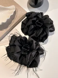 Close-up of black oversized flower hair claws with feather and rhinestone details.