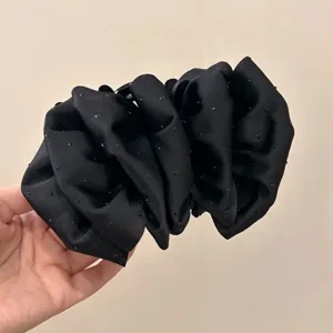 Close-up of large black scrunchie hair claw clip with shimmering rhinestones