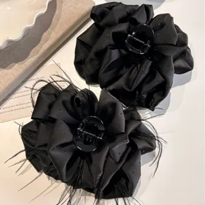 Large black bow hair claw clip with feathers and starry dots for elegant styling