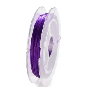 Detalle de primer plano de hilo elástico morado enrollado en bobina transparente para manualidades DIY.