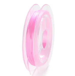 Primer plano detallado de hilo elastico rosa vibrante enrollado en carrete transparente.