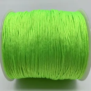 Close up detail of fluorescent green weaving jade cord wound neatly on spool for handmade crafts.