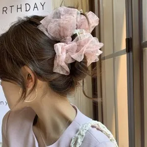 A detailed view of a pink floral ballet-style bow hair claw clip worn by a model