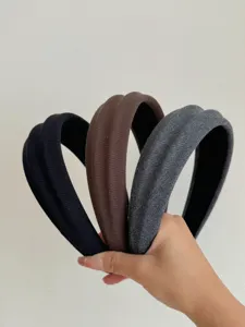 Primo piano di tre cerchietti imbottiti in tessuto strutturato in nero, marrone e grigio.