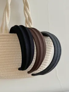 Primo piano di tre fasce larghe in tessuto nero, marrone e grigio appese a una borsa