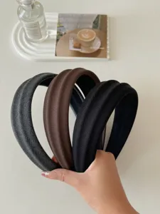 Dettaglio di tre cerchietti larghi in tessuto a righe nei colori grigio, marrone.