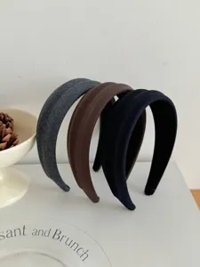 Dettaglio di tre cerchietti in tessuto a righe nei colori grigio, marrone e nero, stile alto.