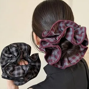 Detailweergave van grote geruite wollen scrunchies voor haarknotjes en paardenstaart kapsels.