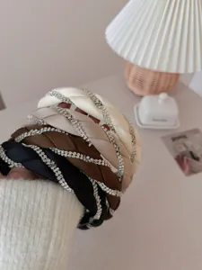 Detailed view of braided rhinestone headbands in black, brown, beige, and cream