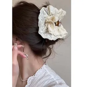 Close-up detail showing a cream lace scrunchie-style hair clip in a ballet aesthetic.