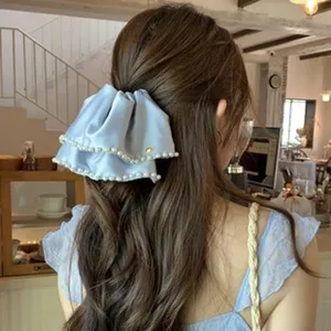Detailed view of a ballet style light blue satin bow hair clip with pearl trim