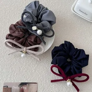 Detailopname van elegante Koreaanse wollen haarelastiekjes met parel- en strikdecor.