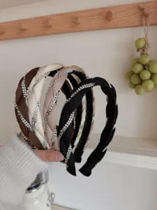 Close-up of braided headbands with sparkling rhinestones in assorted neutral colors.