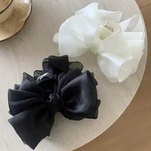 Close-up of black and white ballet style satin bow hair claw clips on a table