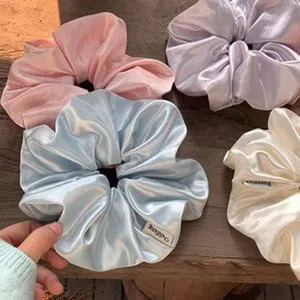 Gedetailleerde weergave van pastel satijnen scrunchies met zijden textuur op hout