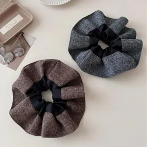 Gedetailleerde weergave van stijlvolle grijze en bruine wollen scrunchies met stof