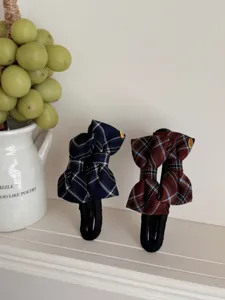 Detail view of two retro plaid bow hair clips in navy and brown fabric on a shelf