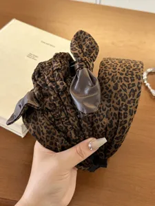 Detailed close-up of a stylish leopard print velvet headband with an elegant bow detail.