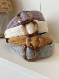 Detailed stack of knitted winter headbands in four colors with amber ring accents