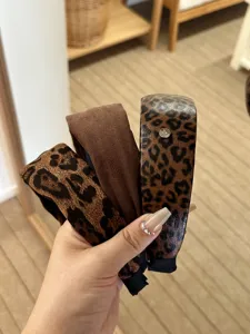 Detailansicht stilvoller Haarbänder mit Leopardenmuster und in Braun, in der Hand gehalten.