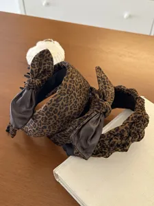 Close-up detail of two stylish leopard print bow headbands on a rustic wooden table