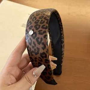 Detailansicht eines vintage breiten Haarreifens mit Leopardenmuster und Metall-Logo