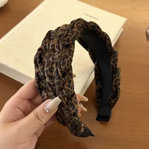 Detailed texture of a wide braided velvet leopard print headband with sponge padding