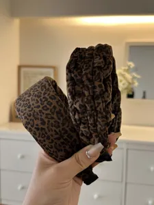 Detailed macro view of a leopard print velvet braided padded headband held by hand.