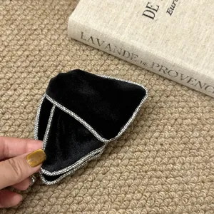 Κοντινό πλάνο μαύρου βελούδινου scrunchie με κομψή αλυσίδα από λαμπερά στρας και σχέδιο