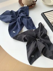 Detailed view of navy blue and black polka dot scarf scrunchies on a stylish table
