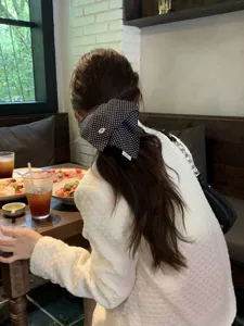 Black and white polka dot hair scarf scrunchie on a ponytail in a lifestyle setting