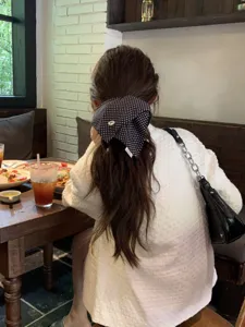 Back view of a woman wearing a black and white polka dot hair scrunchie in a cafe