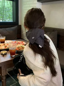 Detailed view of a black polka dot scarf scrunchie on a ponytail in a cafe.