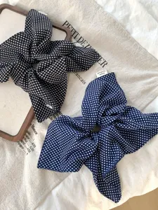 Detail view of black and navy blue polka dot scarf scrunchies on linen background.