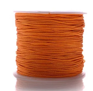 Detailopname van een helder oranje nylon gevlochten koord op spoel voor DIY sieraden.