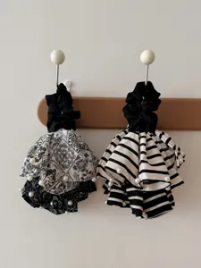 Close-up detail of vintage black and white fabric scrunchies with paisley, stripes, and pearls