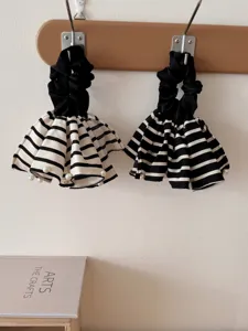 Vintage black and white striped scrunchies with elegant pearl accents hanging on hooks