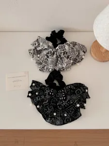 Detailed macro view of black and white paisley pattern scrunchies with elegant pearl accents