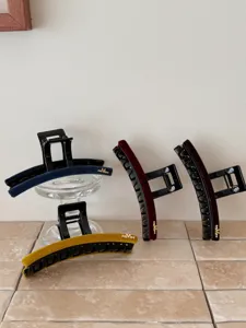 Détail de grandes pinces à cheveux en velours multicolores avec ornement M doré chic.
