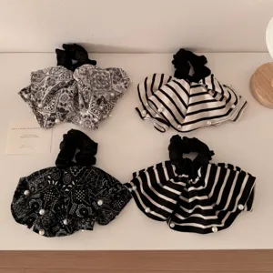 Set of black and white paisley and striped fabric scrunchies with pearl accents.