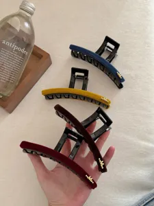 Vue détaillée de grandes pinces à cheveux en velours avec emblème M doré pour la coiffure