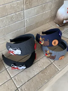 Close-up detail of four wide embroidered puppy headbands with decorative large buttons