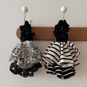 Elegant black and white paisley and striped tiered hair scrunchies with pearl accents.